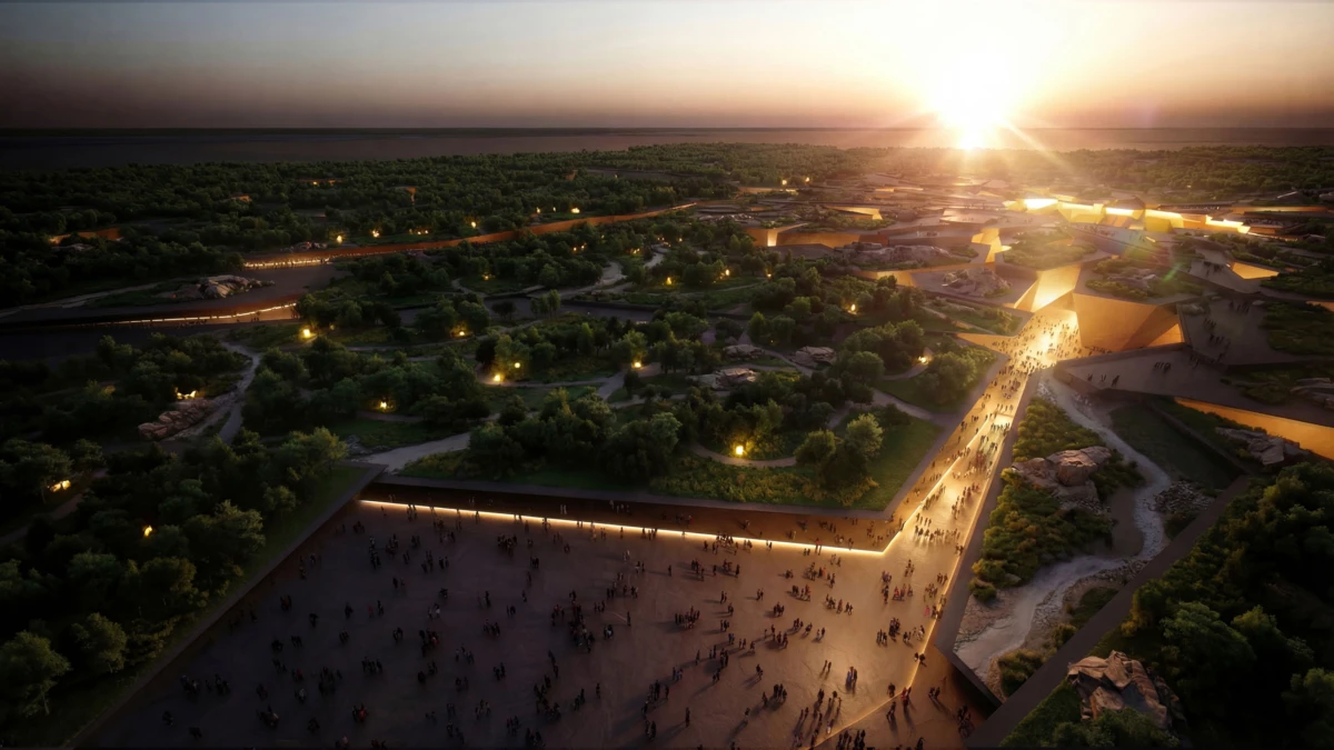 Aerial view of illuminated pyramid complex in a park at sunset; crowds walk along a lit causeway toward the central pyramid.