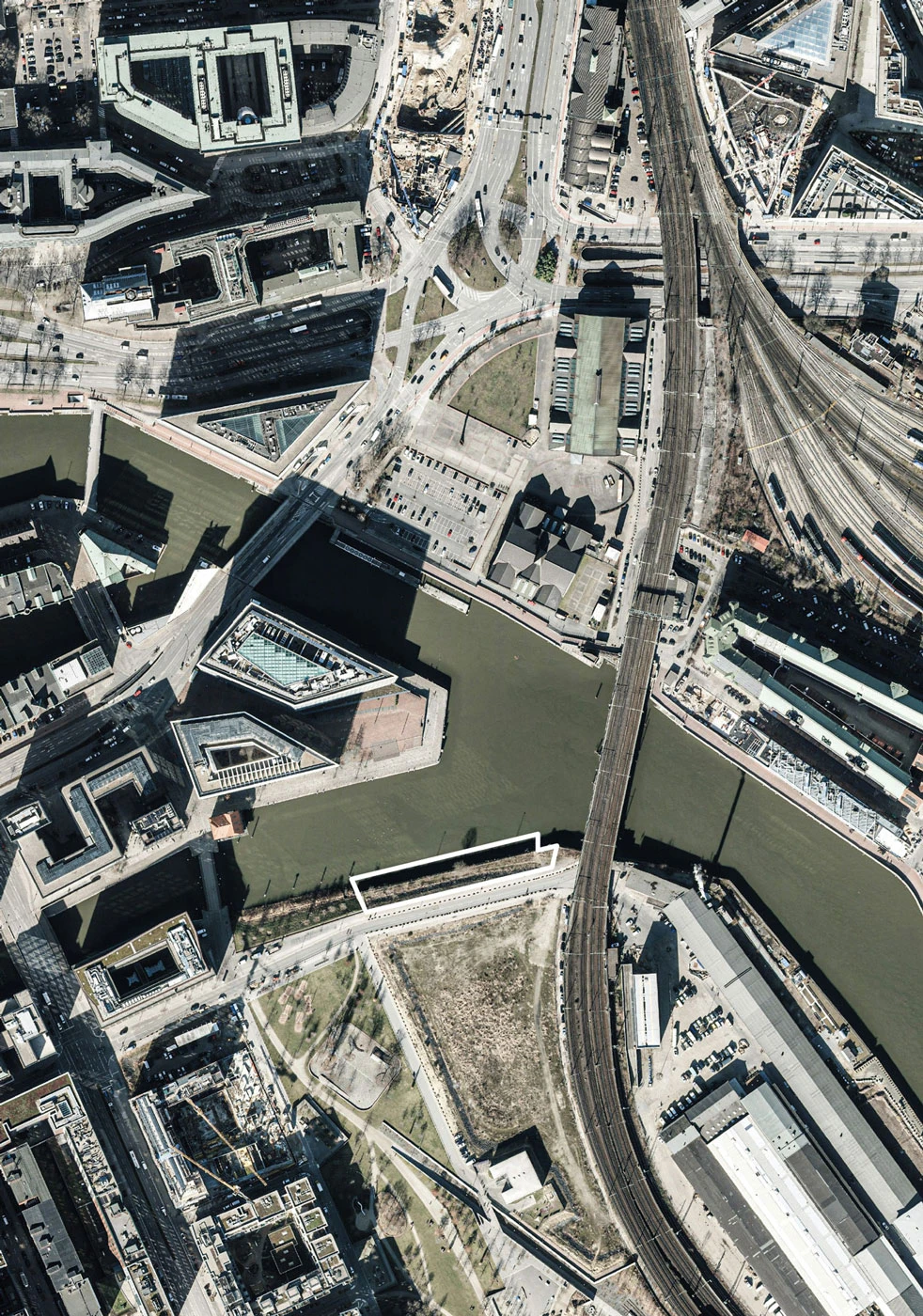 Aerial view of a dense urban waterfront with a curved railway viaduct crossing the river and multiple bridges.