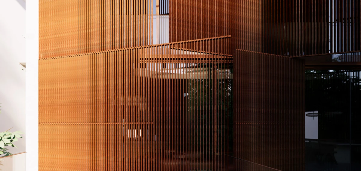 Orange vertical slatted metal screen on a modern building exterior, forming a lattice facade beside glass walls.