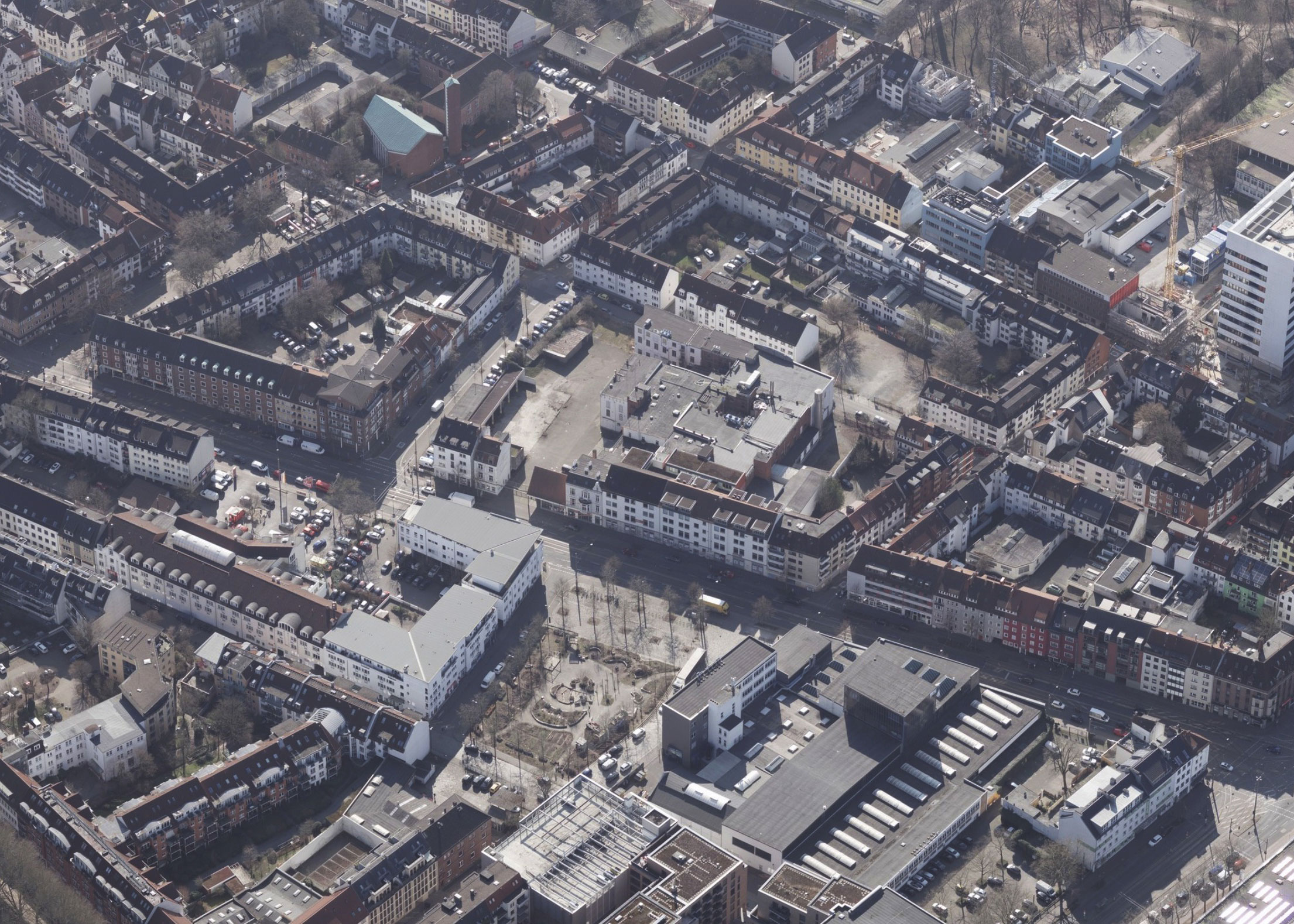 Aerial view of a dense urban area with terraced houses, apartment blocks, and a central square.