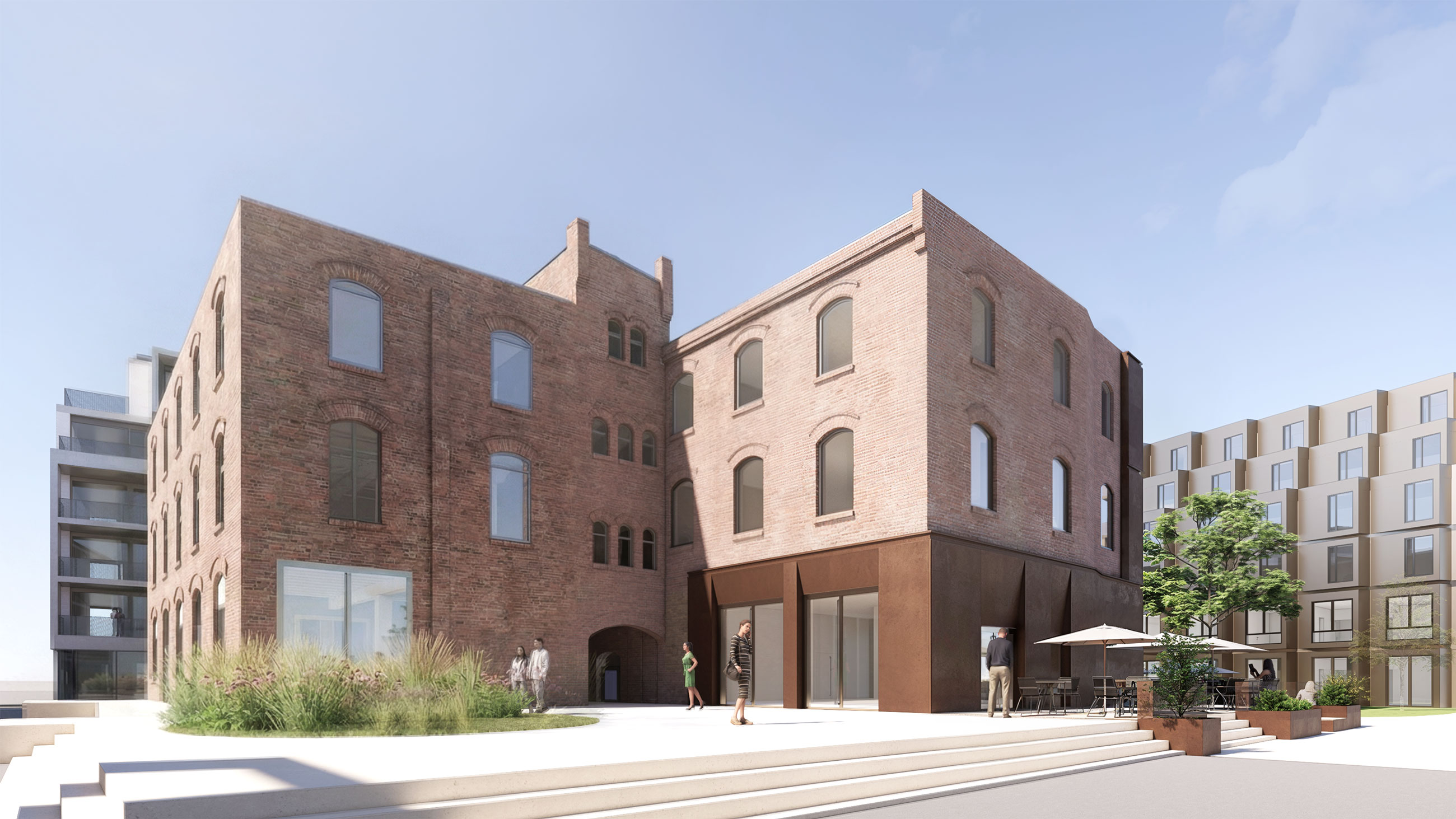Two brick buildings with arched windows flank a paved urban plaza; pedestrians walking near storefronts and an outdoor cafe.