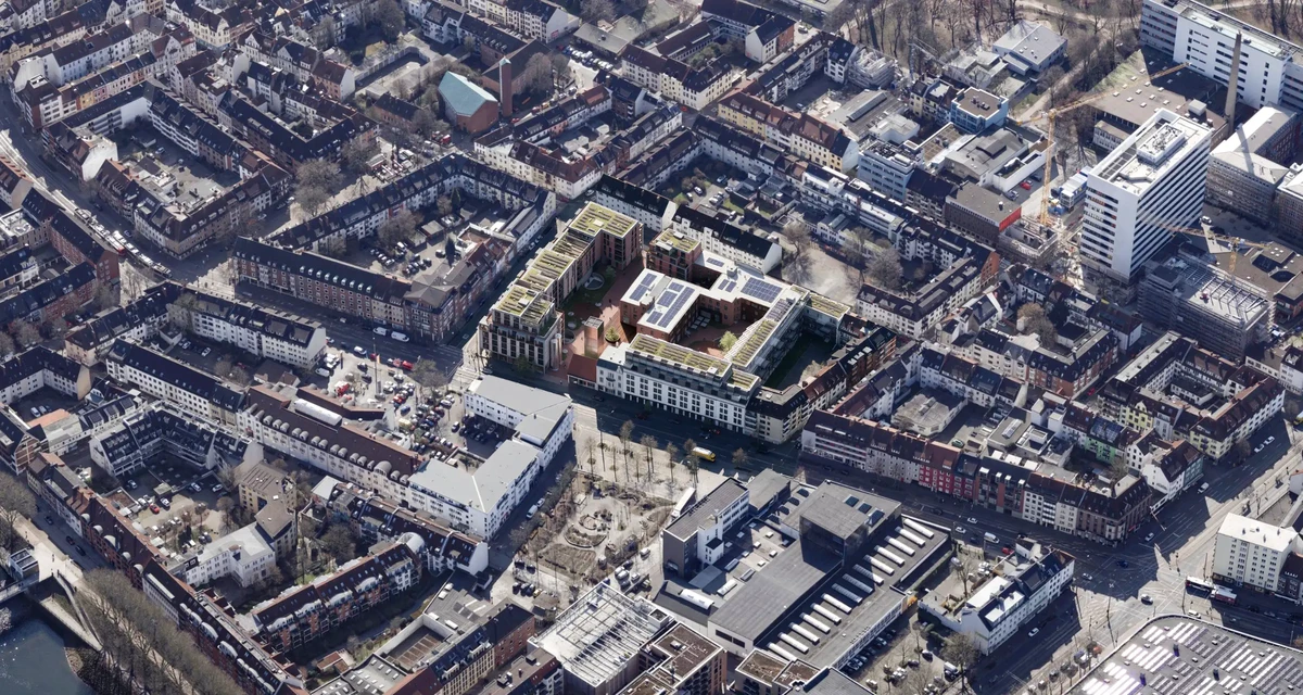 Aerial view of a dense urban neighborhood centered on a U-shaped apartment complex with an inner courtyard, surrounded by brick buildings.