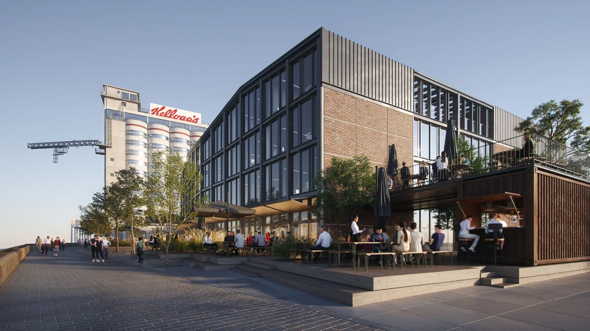 Modern brick-and-glass building with a two-level outdoor terrace and café, crowded with people along a waterfront promenade.