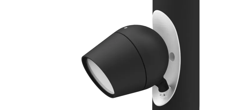 Black cylindrical outdoor wall spotlight mounted on a vertical surface, projecting outward.