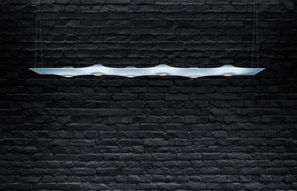 Suspended wave-shaped pendant light with multiple recessed bulbs against a dark brick wall