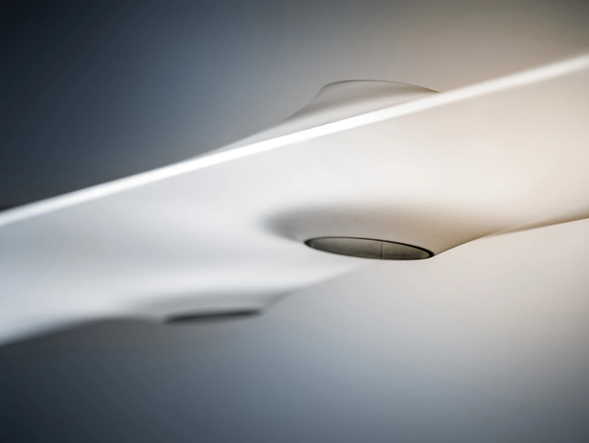 Close-up of a white curved plastic component with a circular recessed pivot, on a soft gradient background.